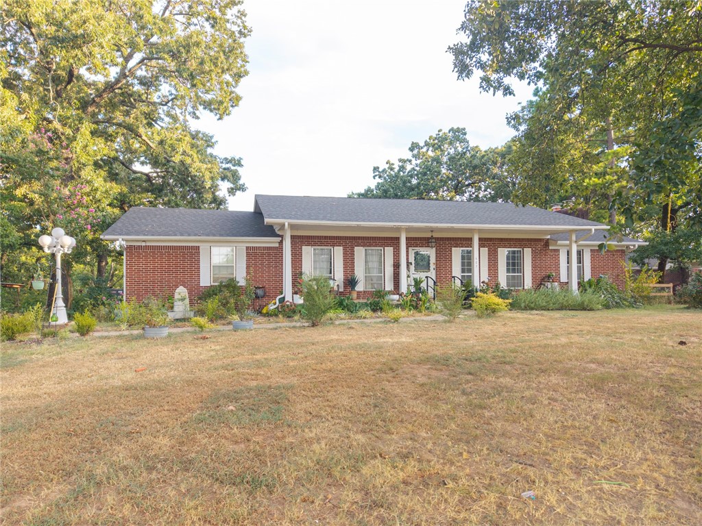This traditional-style red brick home, complemented by beautiful white shutters and columns, is situated on approximately 2 acres in Charleston. The property is enhanced by mature trees, including nine fruit trees, and features a rain barrel. Inside, the residence boasts four spacious bedrooms with three designated desk areas, and ample walk-in closets, providing generous storage options. The open floor plan encompasses a large living room with a wood-burning brick fireplace, a dining area, and a retro kitchen! An oversized covered patio adjacent to the kitchen offers an ideal setting for evening dinners while enjoying scenic views. The finished basement includes a kitchenette, and wood-burning fireplace, making it a perfect game room. Additionally, a detached workshop equipped with electricity provides an excellent space for a home business or extra storage.