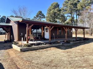 Rustic cabin style home on large 1.5 acre tract surrounded by large trees. 2 car outbuilding with electricity. 1120 sq ft home with large front and back porches to enjoy. Inside features new updates including flooring, cabinets, fixtures, and more. 3 bedrooms 1.5 bathrooms, open concept living room and kitchen. Circle drive, new roof, new central H/A, 2 car carport. Close to downtown lamar and close to I40. Come check it out to see the beauty of this home, and all it has to offer.
