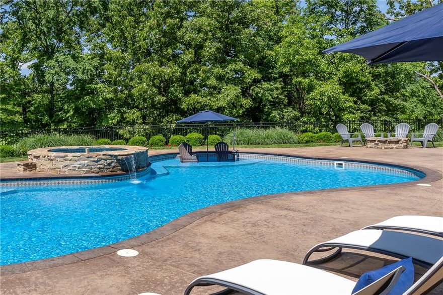 This stunning estate in Hidden Springs offers unparalleled luxury on 2 private acres close to downtown Bentonville. With 5 bedroom suites, each with a private bath, this home is designed for refined living. The primary suite features a sitting area overlooking the grounds, spa-inspired bath, and dual closets, with access to a private office. The gourmet kitchen boasts a WOLF 8-burner gas range, double islands, and SUB-ZERO built-in refrigeration. The lower level includes a game room, full kitchen, guest suite, and dance studio, with walkout access to the resort-style pool. Enjoy outdoor living at its best either poolside or on the activity court shooting hoops, playing pickleball or tennis. There are tons of different outdoor spaces to choose from to relax or dine al fresco on the covered patio. A circular drive welcomes you to the property. There is an additional 2-car garage and workshop off the drive. Enjoy living minutes from downtown Bentonville and trail systems in this true masterpiece of luxury living.