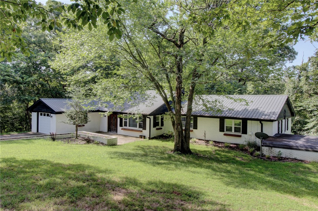 Enjoy peaceful country living just minutes from the heart of Fayetteville in this spacious home on a sprawling, private 10-acre lot. With multiple flexible living areas—including a spacious family room and a cozy second living space—there’s room for everyone to gather or spread out. The large kitchen offers generous storage and prep space, while the oversized laundry/mudroom adds function to everyday living. Outside, you’ll find a 30x40 detached shop perfect for hobbies, storage, or home-based business needs. The tree-lined acreage provides natural privacy, space to roam, and a true escape from city hustle—yet you're only a short drive to shopping, dining, and the University of Arkansas. Whether you're looking for a peaceful retreat, a space to grow, or a place to entertain, this one-of-a-kind property offers rare versatility and value in the amount of rooms which include a 5th room that would make a great office.