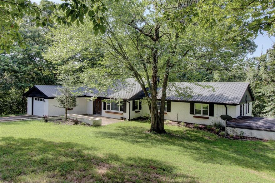 Enjoy peaceful country living just minutes from the heart of Fayetteville in this spacious home on a sprawling, private 10-acre lot. With multiple flexible living areas—including a spacious family room and a cozy second living space—there’s room for everyone to gather or spread out. The large kitchen offers generous storage and prep space, while the oversized laundry/mudroom adds function to everyday living. Outside, you’ll find a 30x40 detached shop perfect for hobbies, storage, or home-based business needs. The tree-lined acreage provides natural privacy, space to roam, and a true escape from city hustle—yet you're only a short drive to shopping, dining, and the University of Arkansas. Whether you're looking for a peaceful retreat, a space to grow, or a place to entertain, this one-of-a-kind property offers rare versatility and value in the amount of rooms which include a 5th room that would make a great office.  $10,000 Credit toward Buyer's closing cost or updates.