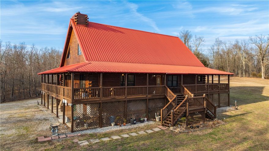 Exceptional 3-bedroom 2.5 bath Log Home with stunning Ozark Mountain views and quality craftsmanship throughout. Features soaring ceilings with Colorado timber rafters, pine wood ceilings, cedar accents, custom stone fireplace, and an open kitchen with a 4'x12' island. A dedicated office sits just off the kitchen and the primary suite includes a relaxing heart shaped double bathtub. Exterior highlights include 6" "D" style log construction and approximately 248'x8' of wrap around covered porch with hot tub. Outbuildings include a detached garage with loft and second washer & dryer connections, three bay carport attached to the 2 car garage, a 20'x30' workshop, 20'x40' heated/cooled man cave(pool table conveys), and an additional 20'x40' enclosed space. Property Boasts 76+/- acres of the Ozarks with mature trees and a pond.