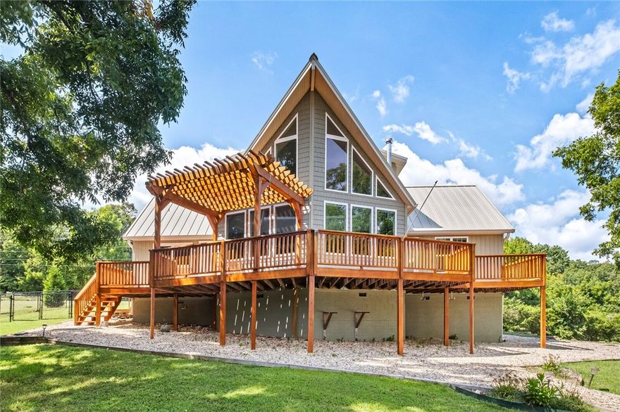 Enjoy quality craftsmanship in this relaxing 1 acre oasis with year-round Beaver Lake views in a 3 home gated community. Open concept layout with expansive windows and large adjacent outdoor deck with pergola allow for comfortable entertaining and an abundance of natural light. 1 mile to the War Eagle Marina. The rich warmth of hardwood floors flows throughout the living spaces, complemented by unique touches like a repurposed front door and sliding barn doors. This floor plan has flexible spaces to suit just about anyone. There are potentially 2 primary bedrooms, one on the main floor and one on the upper floor or the upper room could be used as an office or second living space. The kitchen is both stylish and functional, boasting high-end KitchenAid appliances, farmhouse apron sink and ample workspace with an island. An enclosed breezeway connects the home to the garage. **More pictures coming soon!**