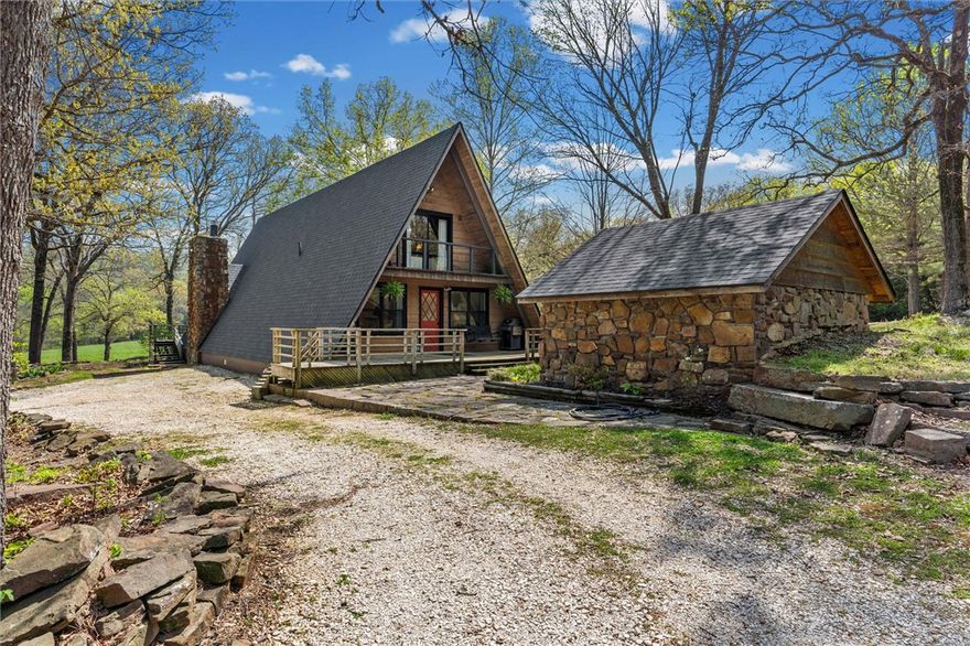 Whether you are looking for a permanent home or a weekend retreat, this property has a lot to offer. Surrounded on three sides by rolling hills and natural forest, the peaceful valley setting is beautiful in all seasons, but stunning in the fall. Minutes from Historic Canehill, the remodeled A-frame home sits just down a well-maintained gravel road with easy access from Fayetteville, Ft. Smith, or Siloam Springs. Nice mixture of woods and open fields along with a pond and wet weather creek. ATV trails run throughout the property. The end-of-the-road location offers privacy, seclusion, and peace. The charming cabin has been completely remodeled but retains the 1970s charm with its vaulted ceilings, wall of windows, stone fireplace, and original pine floors. Don’t miss the recent (2025) barn conversion with its additional bath, full kitchen, and extra storage. There is a water well that is plumbed to supply the A-frame, guesthouse, and gardens. The main house is also plumbed for City of Lincoln water.