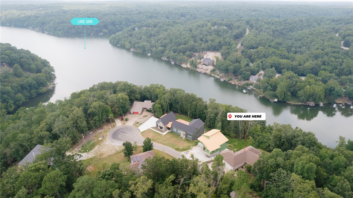Dreamy Lakeview Retreat on Lake Ann! This one-of-a-kind home features 5 generously sized bedrooms + an office/flex space + 3 full bathrooms. The 2 livings areas, 2 FULL kitchens, and 2 laundry areas, make it particularly ideal for larger families or multi-generational living. The primary bedroom is a true sanctuary with seasonal lake views, oversized bathroom and 3 spacious closets. Each level has a split floor plan ensuring you never feel cramped in the space. TONS of extra storage throughout! The handicapped accessible wraparound deck leads directly to the hot tub and outdoor oasis. Stunning windows in the living room and sunroom provide expansive lake views year-round. Sandwiched between the Back40 and Summit School trails, access is just down the road on Sandhurst Dr. Lake Ann Boat Ramp is only a 5 min drive. New roof in 2021 and septic was pumped + inspected in 2023. Outdoor shed + raised garden bed + so much more! Currently operates as a successful STR, furnishings negotiable separately as a package deal.