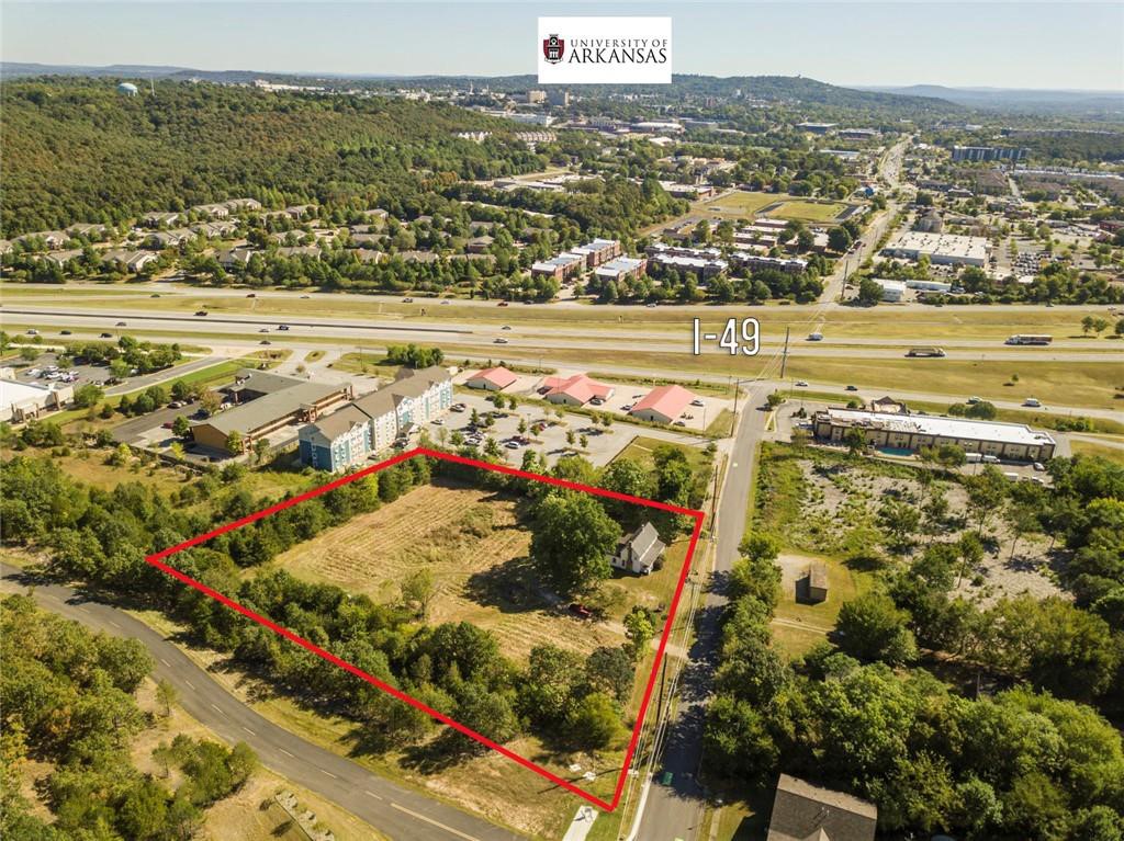 This is a rare opportunity to own 2 acres zoned C2 that adjoins Centennial Mountain Bike Park—home to over 228 acres of cyclo-cross & mountain biking trails. Open your back gate & step directly onto a world-class trail system. The property is surrounded by commercial growth including hotels, motels, restaurants, storage facilities, & multi-family developments. Just minutes from I-49 & located in one of Fayetteville’s fastest-growing areas, this site is ideal for a mixed-use project, destination retail, food park, or outdoor-focused business. Inspired by concepts like Container Park in Las Vegas, this site is perfect for creative developers looking to tap into Northwest Arkansas’ strong outdoor recreation & tourism market. Bonus Historic Feature: The land includes a historic home known as “The Old Tharp Place,” originally built circa 1844 & used as a Red Cross hospital during the Civil War. While the structure is in poor/fair condition, it offers the potential for restoration & added character to your development.
