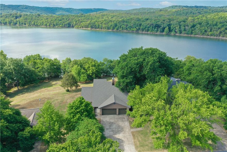 Custom built home with Table Rock Lake lake front lot and view! Owner kept lot topography and north/south facing lot in mind designing this home. Level entry to main level: master suite, master bath with walk in shower, separate tub and accesses a flex room off of the foyer. Open concept living with a double sided fireplace between living room area and dining area. Kitchen has ample custom oak cabinets, writing table with lake view and access to deck. The main level also has a sunroom facing the lake. Large utility room with rinse sink, pull down ironing board, oak cabinets and space for an upright freezer or frig. Did I mention the half bath? The upper level is currently being used as an office, private deck with lake view, ample storage, and full bath. The lower level is equipped with kitchenette, hot tub room, bedroom, full bath, family room with insert, library, flex space and access to another deck. Need more bedrooms - no problem! Ample parking in front of the three car garage. New roof in 2022. Lovely!