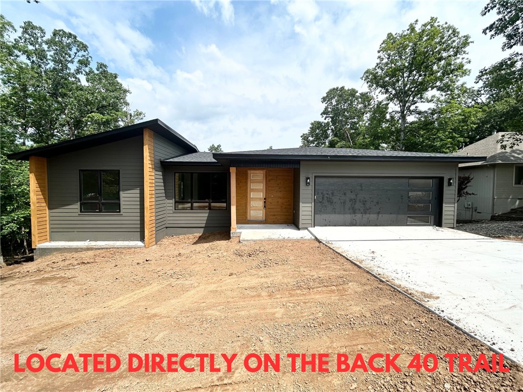 New construction on a spacious .31-acre wooded lot with a level backyard. This modern single-level home is located directly on the Back 40 Trail and adjacent to the trail crossing, with easy access to Lake Rayburn, Metfield Golf Course, and Downtown Bentonville. Bentonville schools! Step inside to discover a bright open floor plan with high-end finishes throughout. The kitchen features sleek stainless steel appliances (including a gas range), and stunning custom cabinets complemented by 3 cm quartz countertops. The luxurious primary bath boasts a double vanity, a large custom tile shower, and an oversized walk-in closet. No carpet! Enjoy outdoor living on the expansive covered patio, perfect for entertaining or relaxing in nature. This home combines convenience, style, and comfort in one exceptional package.
