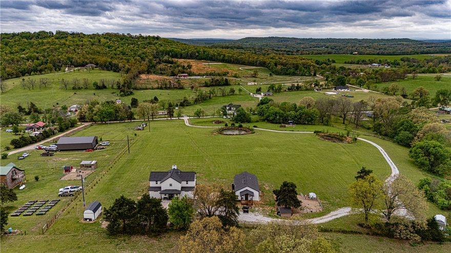 This 8.93 Acre +/- property features a Main home & Guest Home built in 2023! With 1921 Sqft in the main home, head inside from the covered front porch to open concept living w/ wood-burning stove, tons of natural light & wood-look tile throughout. Light & bright kitchen w/ quartz counters, white cabinetry w/ soft close hinges, SS Apps, large center island & walk-in pantry. Rejuvenate in the primary bedrm w/ private ensuite feat: double sink vanity, walk-in shower & dual walk-in closets! Split floor plan w/ upstairs feat: 2nd living w/ built-ins, 2 add’tl bedrms & full bathrm! 912 SqFt Guest Home is open concept w/ 10’ ceilings, natural light, & wood-look tile throughout feat: living rm, full kitchen, laundry rm, 1 Bedrm w/ walk-in closet & 1 full bathrm! Both homes feature covered back patios overlooking the gorgeous property & Arkansas’s rolling hills! 8.93 Ac +/-  gently rolling w/ 2 ponds perfect for nature enthusiasts or hobby farmers! PLUS 2 storage bldgs & main house is prewired for hot tub. Don't miss out!