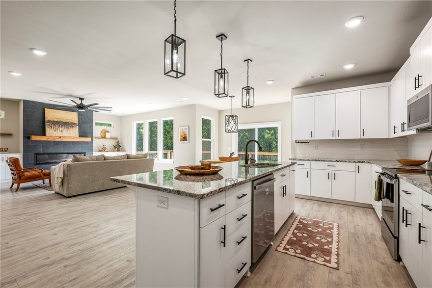 Built in 2023, this light-filled contemporary home offers modern construction in a private wooded setting without the wait. Located on a quiet street in Bella Vista with no homes behind, it provides a peaceful, secluded feel. Inside, expansive windows bring in natural light and showcase the surrounding greenery. The open layout is ideal for everyday living and entertaining, featuring granite countertops, a large center island, walk-in pantry, and sleek electric fireplace. The primary suite includes a soaking tub, tiled walk-in shower, and spacious walk-in closet. A dedicated office or study adds flexibility. Enjoy the generous backyard and elevated cedar-post deck overlooking the trees. Just a short walk to Highlands Golf Course with easy access to I-49. Recent upgrades include fencing, LeafFilter gutters, custom mantel, floating shelves, keyless entry, and privacy shades.
