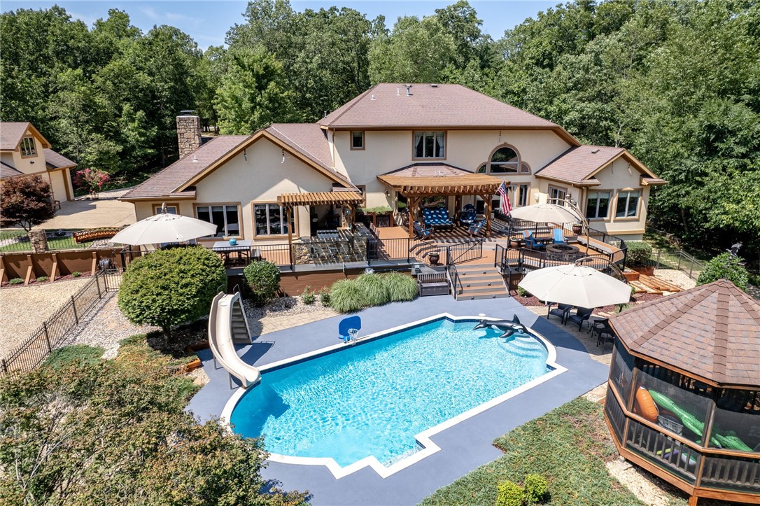 Amazing Bentonville property that feels like a resort from the moment you turn onto the private circular drive. Main home boasts over 4400 square feet. Detached guest home has 1114 square feet. Main house has a sprawling feel & soaring 2 story ceilings in the living room. Oversized primary bedroom w/fireplace & seating area. Fully remodeled primary bath w/gorgeous white vanities, luxurious, free-standing soaking tub, & beautiful, tiled walk in shower. Great flex space off the primary bath currently being used for exercise room. From there, walk out to the pristine hot tub for a relaxing soak. Views from the two story windows in the living room overlook the in-ground salt water pool, a lovely gazebo, koi pond, & personal playground! Guest house has living, kitchenette, bedroom, full bath, bonus room, plus heated & cooled shop in the basement. This pristine property on 4.4 acres is a must see & is just under 1.5 miles to Coler trail system.