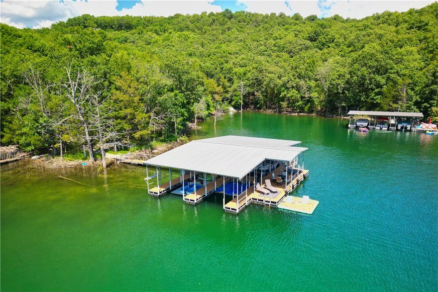 Soaring 28.5-foot floor-to-ceiling windows w/ slate stone pillars, & a striking 24-foot stone fireplace define the architectural grandeur of this one-of-a-kind mid-century modern lake house retreat. Nestled in the tranquil no-wake zone of Sailboat Cove with direct access to a private 4-slip dock, this property blends iconic design with cutting-edge amenities for modern lakeside living. Sold fully furnished w/ an updated kitchen & primary bath, large-format tile over a Schluter waterproof subfloor, & updated LED lighting. Tech upgrades include a whole-house and dock sound system, new security with cameras, water sensors w/ remote shutoff, pro Wi-Fi and cell booster, and an EV charging station. The private 4-slip dock (two 30’, one 26’ with flat toy lift, one 24’ with WaveRunner ports) includes electricity, Wi-Fi, and security. Located near Lost Bridge airstrip (40A) with access to community amenities: pool, clubhouse, fitness center, and playground. This rare architectural gem offers an unmatched lakeside lifestyle.