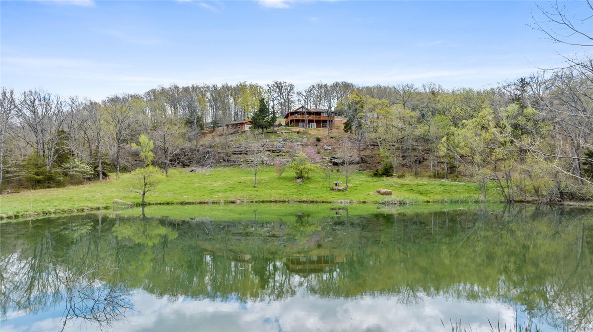 OZARK PARADISE! If you are looking for your own private & remote setting then this is it. Very private & serene property at the end of a winding lane along the mountainside that opens to gorgeous panoramic views of the Ozark mountains. This log home sits high on the bluff overlooking your own private stocked pond and breathtaking views of the Ozark Mountains. This property is nearly 15 acres with an additional 10 acres that could be purchased seperately. The D Log home is made of 8" Northern White Cedar Logs shipped from Maine & constructed on site. Knotty Pine vaulted celings in the open concept main living/kitchen area. 2 Bedrooms & 2 baths on the main level. Wood floors & stained stone-like floors give this a true mountain cabin feel. Downstairs is a full finished walk-out basement with second living area & kitchenette with bonus area. Covered Decks on 3 sides. Additional 1200 sq/ft building that could be guest house or shop. Abundance of wildlife & only 20 minutes from Fayetteville. Endless Possibilites!
