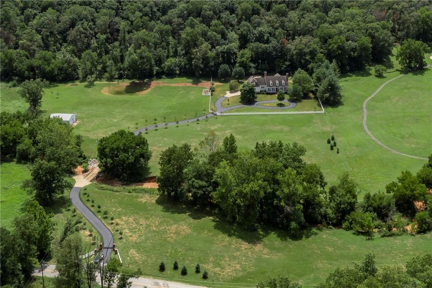 Rare Large Acreage Estate in North Bentonville!  “Redbud Estate” is a Southern Living Inspired Dream Home situated on 16.85 acres in the desirable area of Punkin Holler near Coler Creek Mountain Preserve! This one-of-a-kind property is minutes from Downtown Bentonville and is a melody of southern-living eloquence intertwined with sleek and modern updates! Driving up the long winding tree lined driveway leading to the historic inspired built home, you are greeted with privacy and the sights and sounds of nature. Gorgeous interior with library, formal dining, Chef’s kitchen, and private Master Suite with luxurious spa-inspired bath-a stunning wet room/steam shower/soaking tub!  Upstairs has additional bedrooms and flex rooms. The grounds feature a wet weather creek, 40 x 40 barn, beautiful mature trees and landscaping, heated pool, hot tub, firepit, and amazing outdoor living and entertaining area! This is a one-of-a-kind rare private retreat in the heart of NW Arkansas!