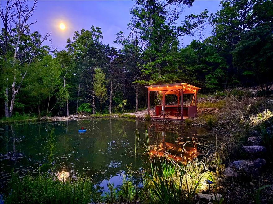 Private mountaintop sanctuary in Holiday Island, AR—where elevated living meets panoramic views. Set on 32.8 acres, this 2005 custom-built retreat offers ultimate privacy, soaring ceilings, two fireplaces, and a second living room with wet bar. Andersen hurricane-grade steel sliders open to expansive wraparound decks—your front-row seat to sunrises, sunsets, and starlit skies. Indulge in a hot tub under the stars, stroll terraced gardens, or fish your private pond with fountain. A whole-house generator, new HVAC systems, new roof, and fully inspected well and septic offer peace of mind. Dreaming of a hobby farm, guest cottages, or multigenerational living? Covenants allow one subdivision with multiple build-ready sites already in place. Just minutes to the championship golf course and clubhouse, this estate blends seclusion, beauty, and lifestyle. More than a home—it’s your private resort, your retreat, your legacy. Come claim your mountain kingdom.BY APPT ONLY