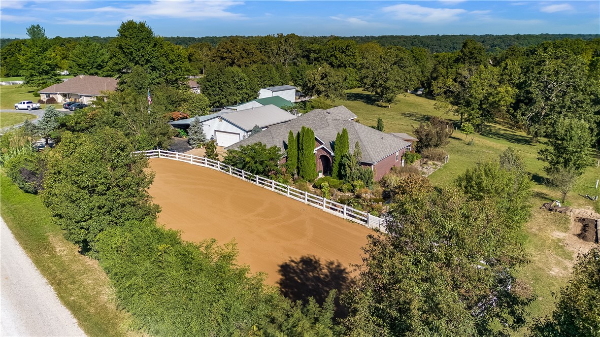 Experience the perfect balance of comfort, function, and country living with this all-brick 4-bed, 2.5-bath home on 5.31 picturesque acres with a pond. Built in 2006, this property is a horse ownerās dream, featuring a 2ā3 stall barn with a full fly-control system, hay barn, tack building, and a fully plumbed, drained dressage arena desigend for training & performance. The home offers an open floor plan with formal dining, a spacious eat-in kitchen with granite counters, and abundant storage. Upstairs includes a bedroom and half bath ideal for a second living area, playroom, or office. Enjoy peaceful views from the large back deck, screened detached sunroom, cozy gazebo with firepit & seating area. Additional features include three shops, four garage spaces, 46ā covered RV and trailer parking, and a 2-bed, 1-bath guest house located inside one of the shop buildings. A whole-home backup generator provides peace of mind. This exceptional property combines country charm, equestrian amenities, and everyday comfort.