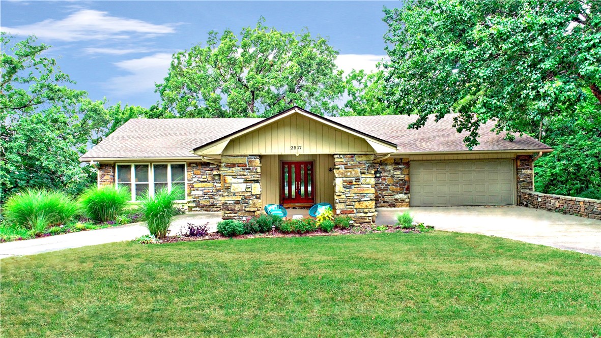 Live in the middle of Fayetteville but feel as if you're in the country surrounded by a wall of mature trees. A welcoming and spacious floor plan on two levels with large windows and plenty of sunlight gives beautiful views of the sunset and Fayetteville's lights in the fall and winter. The upper level's main room with a wood-burning fireplace leads out onto a glass-enclosed reading nook with the feel of a treehouse. The primary suite is spacious as it overlooks the yard with nearly floor-to-ceiling corner windows. The downstairs level boasts a family room with large bookshelves, a wet-bar, a workout or yoga room and a very large storage area that doubles as a storm shelter. Walking out of the basement you will see a glass, closed-in sunroom with large outdoor deck. This home is just five minutes from the main attractions in Fayetteville from Gulley or Wilson Parks to the University of Arkansas, Dickson Street, the Fayetteville Square with its farmer’s market, the mall and shopping areas, and Lake Fayetteville.