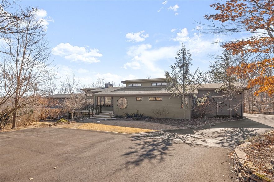 The best kept secret in North Bentonville! Minutes from Coler, on 7 wooded acres, this architectural masterpiece better known as “Firefly” sits w/  a private, gated drive featuring 3 bdrms, 3.5 baths, all on main level. This designers dream w/ open kitchen, living room, formal dining & wet bar showcasing picture windows & large, covered porch w/ pizza oven are perfect for entertaining or a peaceful day/evening at home birdwatching or enjoying the views. Retreat to the master suite w/ wall-to-wall windows & spa-like master bath w/ heated bathroom floors & towel racks, steam shower & designer closet. The double-sided fireplace make the living room & office super-cozy & perfect for reading, working or relaxing in the 2nd living room. Lower level has a great bonus room open to pool & alfresco area w/ heated, gunite pool & a shop for all of your hobbies or storage needs. This home is fully ADA compliant complete w/ lift & has underground storage & safe room. So many upgrades and luxury amenities on this amazing home!