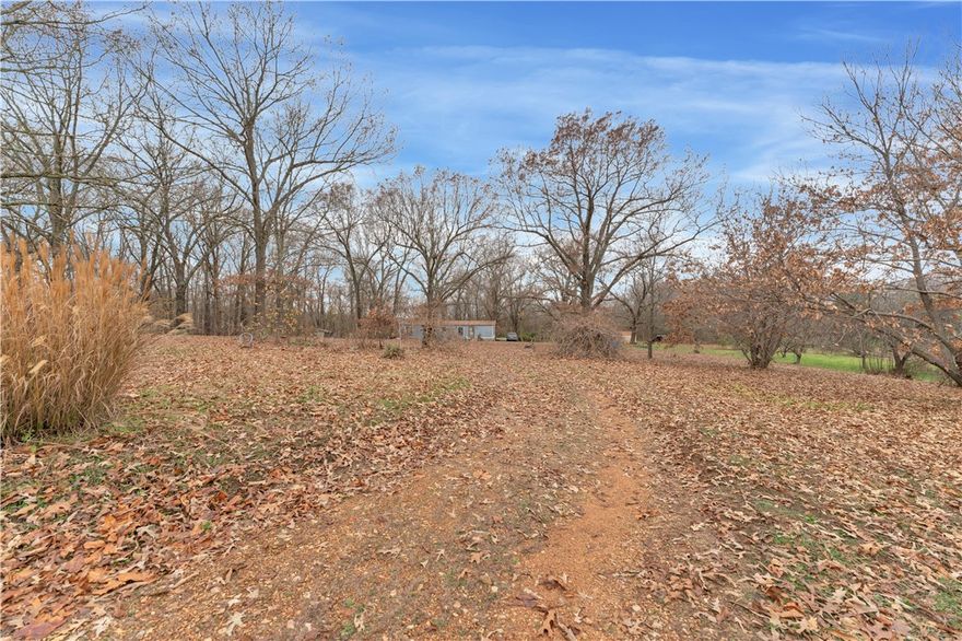 Discover 5.11 acres of land for sale in Springdale Arkansas offering privacy, open space, and a peaceful country setting. This property has been treasured for more than forty years and features a mix of open pasture and mature trees with room for gardens fruit trees and outdoor living. Generations have gathered here, making it a meaningful homestead surrounded by the quiet beauty of Northwest Arkansas.
Now ready for its next chapter, this Springdale acreage offers multiple potential building sites, gentle terrain, and a serene setting ideal for a custom home or private retreat. Water and electric are on site, including two power poles, and a lime sulphur well is present. No septic system currently in place. Existing trailer is not livable.
Located near the end of a quiet loop road, this land provides rural privacy while remaining conveniently close to Springdale, Elm Springs, Cave Springs, Highway 112, and Highway 412. Acreage opportunities like this in Northwest Arkansas are increasingly rare.