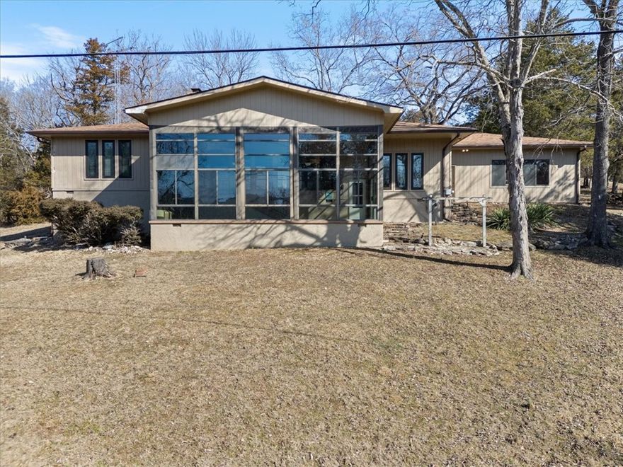 Sprawling lakefront retreat with easy walking access to the waters edge. This large home has lots of interior and exterior entertaining spaces. There is even a swanky wet bar built in for ease of serving guests. The sunken living room is open and inviting with a large stone wall fireplace surround and an entire wall of windows overlooking the totally amazing sunroom and showcasing the landscaped back yard with a lovely year round view of Table Rock Lake. The well appointed Primary bedroom has a private en suite bathroom and multiple closets with additional storage to keep things tidy. There are two nice sized extra bedrooms and even a private office located just off the living room. The kitchen was recently remodeled and updated with new countertops and stainless appliances. Enjoy easy access to the grill in the sunroom with a private staircase from the kitchen. The garage will leave you speechless, plenty of room to park your truck, boat and the golf cart! Island Marina, Pool, Playground & Golf all within 1 mile.