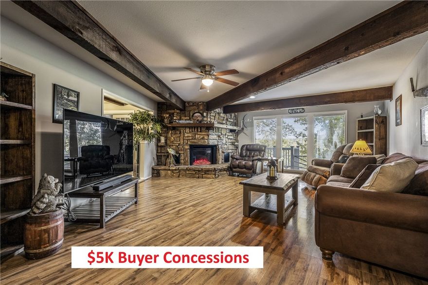 $5,000 BUYER CONCESSIONS being offered.  Delightful ranch-style home, where stone accents & a pergola-covered entry create an inviting first impression. Inside, a stunning natural stone fireplace anchors the living space, complemented by rustic wood beams that add warmth & character throughout. The spacious kitchen features a unique brick accent wall surrounding a 5-burner gas cooktop, w/ample counter space & storage. Large windows bathe the home in natural light. Currently used as a third bedroom, the cozy den includes a built-in Murphy bed, a huge closet, & custom shelving—offering great flexibility for guests or home office use. Step outside to enjoy views of the Kingswood golf course above the scenic "Danger Will Robinson" trail through an expansive sliding glass door. In spring, the yard comes alive with mature trees, shrubs, and colorful perennials blooming in thoughtfully maintained flower beds.  Updates: Water Heater ‘24, HVAC System ‘24, Roof ‘18.  2-bedroom septic system.