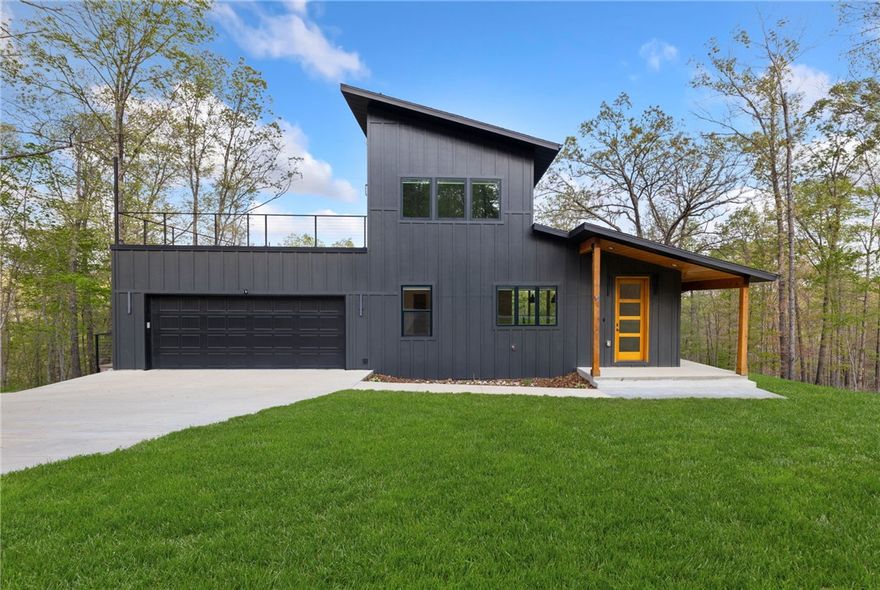 Discover this exceptional modern home in Bella Vista, perfectly situated on a coveted, one-acre double lot. This is a rare find, offering the privacy and space of a large property with the convenience of an incredible location. The home's design features sleek, clean lines and large windows that provide a tree-filled view from every room, giving you the feeling of living in a private, elevated sanctuary.
The home's highlight is the expansive wooden deck, which overlooks a lush canopy of trees, creating a serene and private outdoor living space. Best of all, this property offers direct, backyard access to the renowned Tunnel Vision mountain bike trail. Bike from your back door and connect instantly to Tunnel Vision along with the extensive Bella Vista trail network. This unique combination of modern design, expansive lot size, and direct trail access makes this property a must-see for anyone looking for the ultimate Bella Vista experience.  The garage includes an EV charger for your convenient at home car charging.