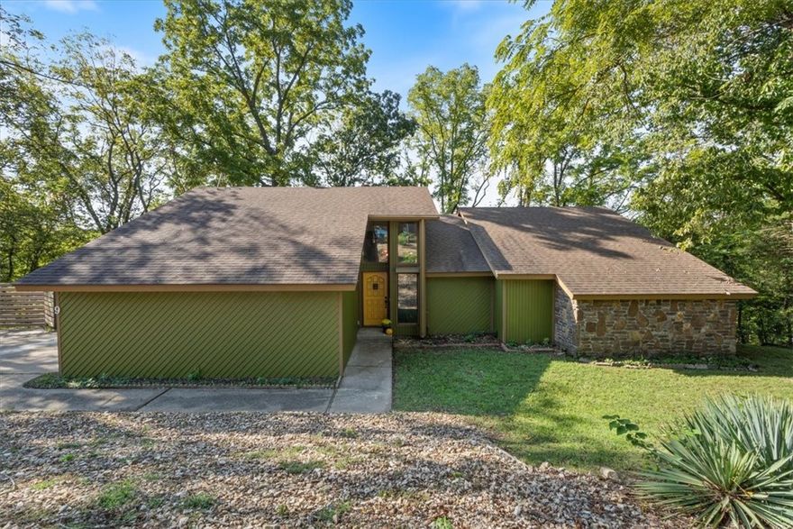 This robust and over-engineered home combines a stylish mid-century modern design, an exceptional location and supreme comfort all in a prime area of NWA. It is ideally situated on over 1/3 of an acre at the end of a quiet cul-de-sac near 71 business, a mere 10 minutes from the Walmart headquarters. This lovely and spacious home features a great room with massive native stone fireplace, wet bar, custom glass chandelier and expansive vaulted ceilings, there is even room for your piano! This open floor plan includes a beautiful sunroom that invites natural light to pour in providing a serene place to relax and escape with 2 private decks overlooking a gorgeous wooded backyard. The bright and airy kitchen was opened up in the remodel and has a lovely dining area with island creating a perfect work flow to the space. Other recent upgrades include a new cedar privacy screen, fresh paint, LVP flooring throughout and even a major bathroom remodel. The oversized two car garage provides convenient parking and ample storage.