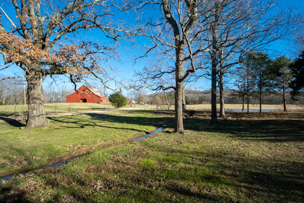 Nestled on this 250-acre paradise is a Vintage farmhouse that boasts five bedrooms, three full bathrooms, two fireplaces, and a magnificent stained deck overlooking The Ozarks. Although the farmhouse is updated, the original charm still exists. This home includes new wood flooring, custom concrete floors in the kitchen and entryway, new stain-resistant carpet in the bedrooms, and new appliances. The windows have a lifetime guarantee, the metal roof has a 50-year warranty, and many other unique features you must see. The stately barn with its fresh, bright red paint surrounded by emerald grass built around 1939 resembles a painting. This 250-acre piece of paradise has pastureland and lush woods, six stocked ponds, natural springs, a waterfall, hiking trails, and a plenty of wildlife. This property offers plenty of room for horses, cattle, goats, or other animals. In addition, a 30x40 shop. You won't want to leave! see 1193833,1193844,1193845