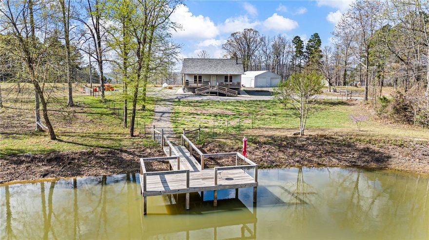 This incredible property is a must see! Built in 2017 and set on 23.46 acres, it delivers the perfect blend of comfort, functionality, and opportunity. A breathtaking 3 acre pond loaded with catfish, largemouth bass, bluegill, and crappie serves as its centerpiece, with full perimeter access, a gravel drive across the dam, wooded trails, and a large dock. Inside, the kitchen, bathrooms, and laundry room feature granite countertops, shaker cabinetry, and a stylish backsplash that ties it all together. Step outside to an expansive deck overlooking peaceful surroundings, with the entire acreage fully fenced for added privacy and usability. A two bay shop with overhead wiring, retractable extension cords, and workbenches offers versatility for work or hobbies. Additional features include an on demand water heater and an owned propane tank. With established fruit trees, garden space, wildlife, and room to spread out, this property is ideal for recreation, homesteading, or creating your own retreat. Truly a rare find!