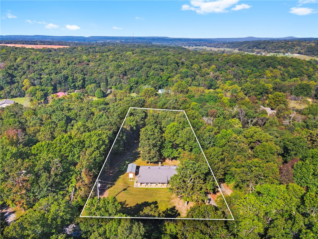 Welcome to peaceful country living just minutes from the heart of Fayetteville! Nestled on nearly 2 acres in the sought-after Wedington Woods community, this 3-bedroom, 2-bathroom home provides the perfect blend of privacy, nature, and convenience. Offering 1,652 sqft of thoughtful space, this home features bamboo flooring, new granite countertops throughout, updated bathrooms, and a cozy wood-burning fireplace. The bonus room is perfect for an office, playroom, or dining. Outdoor living shines here - relax on the large wooden deck overlooking the peaceful, private backyard complete with mature trees and an established fenced area. Raised garden beds are ready for your plants, and plenty of space for your animals. Additional features include a two-car garage, storage building, and a concrete RV parking pad with electric hookup—great for a camper or future ADU. Experience the best of both worlds: the tranquility of country life and the convenience of city access. This Fayetteville gem is ready to welcome you home!