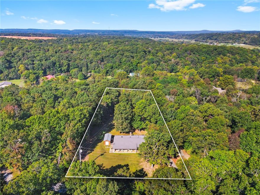 Welcome to peaceful country living just minutes from the heart of Fayetteville! Nestled on nearly 2 acres in the sought-after Wedington Woods community, this 3-bedroom, 2-bathroom home provides the perfect blend of privacy, nature, and convenience. Offering 1,652 sqft of thoughtful space, this home features bamboo flooring, new granite countertops throughout, updated bathrooms, and a cozy wood-burning fireplace. The bonus room is perfect for an office, playroom, or dining. Outdoor living shines here - relax on the large wooden deck overlooking the peaceful, private backyard complete with mature trees and an established fenced area. Raised garden beds are ready for your plants, and plenty of space for your animals. Additional features include a two-car garage, storage building, and a concrete RV parking pad with electric hookup—great for a camper or future ADU. Experience the best of both worlds: the tranquility of country life and the convenience of city access. This Fayetteville gem is ready to welcome you home!
