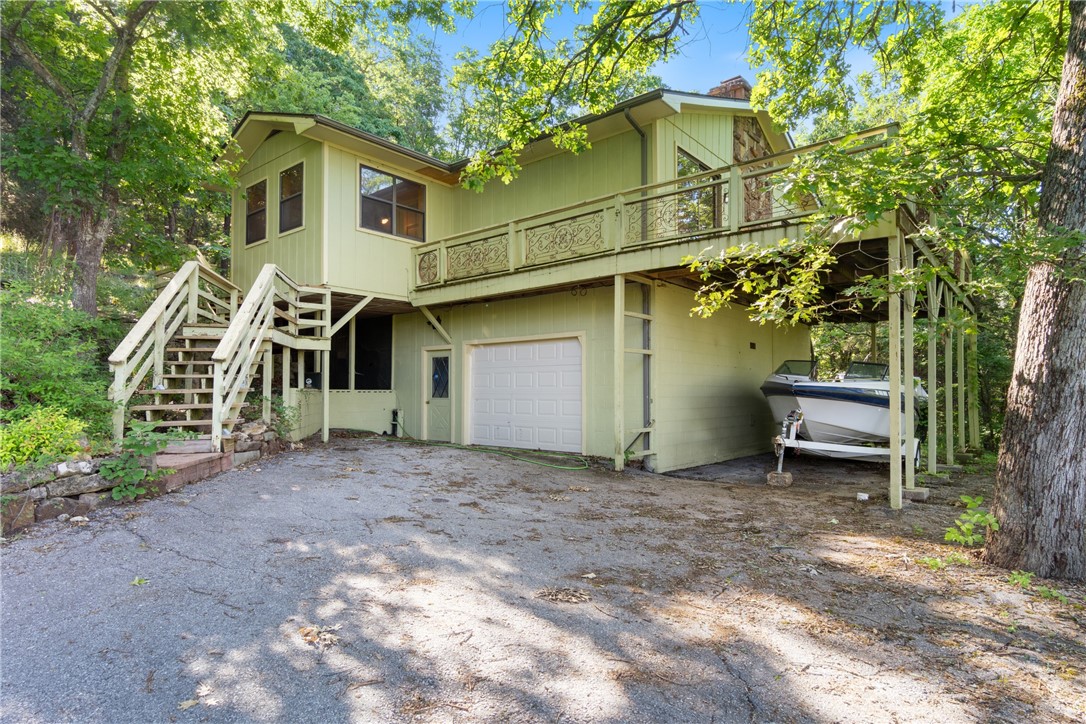 Set on a double lot totaling 0.8 acre, this 2 bed, 2.5 bath home is less than 5 minutes from the Holiday Island marina and 15 minutes from Eureka Springs. A large front deck offers elevated views and a peaceful setting, while the back deck off the sunroom provides additional privacy. The sunroom is wrapped in windows, filling the home with natural light and views. Inside, the open living room is centered around a large wood-burning fireplace, with bamboo flooring throughout most of the home. The galley kitchen includes generous cabinet storage and a pass-through to the living area. The large primary bedroom offers an en-suite bath. Downstairs features a spacious 1-car garage, multiple storage areas, and a bonus room with a half bath—ideal for a workshop, studio, or flex space. The lots include beautiful rock formations, trails, and regular visits from deer and other wildlife. A large asphalt drive offers plenty of parking. A new roof and HVAC in 2023 add efficiency and peace of mind. Don't miss out on this one!