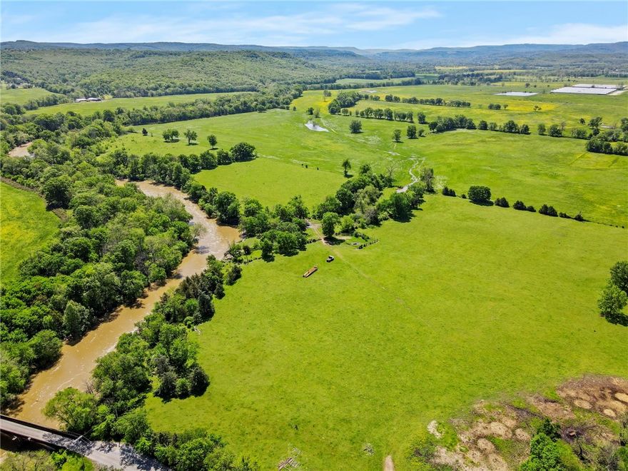 Incredible 224-acre estate w/over half a mile (~3500ft) of White River frontage—just outside Fayetteville. Nature lover’s & sportsman’s paradise w/wildlife, two ponds, breathtaking views & 8,400sf of detached buildings.9,920sf lodge features hand-hewn logs, custom doors, 5 stone fireplaces, stacked stone exterior, geothermal heated floors, metal roof & elevator. Inside: 4 beds, 5 baths, loft & safe room/full separate apartment. Massive 44’ x 36’ great room perfect for entertaining, events, or retreat use. Over 3,800sf of covered porches, balconies & patios. Also on the property are 2 guest homes (~1250sf each, not included in listed square footage), a tiny cabin, greenhouse, barns, goat & horse stables, chicken coops, metal buildings & original homestead water well. Fenced & cross-fenced. Endless potential as a private estate retreat, working farm, or event venue. City water/electric. Built in 2002 with exceptional craftsmanship. Sold as-is, some finishes required. Appointment only. Also listed RES MLS 1308369