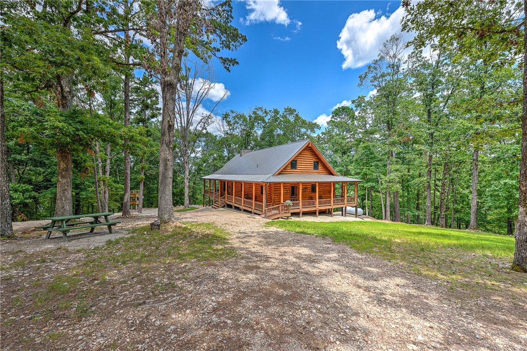 Nestled in the Ozark woods between Eureka Springs & Rogers, AR, this charming log home offers an oasis of peace, calm, & comfort. Just 15 minutes from the vibrant downtown Eureka Springs & moments from Big Clifty Park's boat launch with public access to Beaver Lake, it's a dream for lake enthusiasts. This inviting home features a cozy loft & a walk-out basement, an open concept living area with a warm fireplace perfect for chilly evenings, & chef's kitchen with stainless steel appliances. Step onto the expansive wrap-around porch to savor fresh mountain air, enjoy your morning coffee, or host delightful summer BBQs. The additional guest/in-law home offers potential for visitors or as an income property, while the 26'x30' garage provides space for all your outdoor toys. Spanning approximately 23 acres, this property is a haven for those who love fishing, boating, hiking, or simply unwinding in nature. Don’t miss out on this incredible chance to own your own slice of paradise!