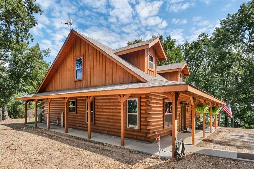 Escape to your private hilltop overlooking the stunning waters of Beaver Lake. Built in 2020, this custom Satterwhite Log Home effortlessly blends with the gorgeous natural setting and features 9 ft ceilings with a first floor primary suite. Thoughtful interior design continues through the open floor plan of the main living area. A cozy living room with a pellet stove for cool evenings and a light filled kitchen boasts quartz countertops, a farmhouse sink, and easy-close cabinets. Upstairs are two bedrooms with walk-in closets and a full bath. 
Outside you will find an inviting front porch that continues around the house to protect you from the elements while a tranquil seating area in the backyard is the perfect spot to relax and enjoy the lake views. Need more space? The 24x24 detached garage with two 10 ft doors provides plenty of space for vehicles and you can invite guests to bring their RV, full hookups offer convenience while they also enjoy the lake view.