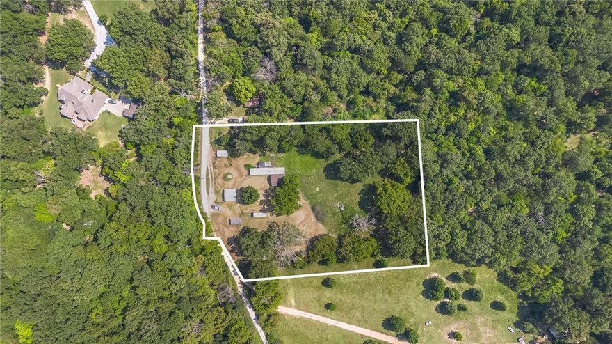 VALUE IS IN LAND. -This flat and ready to be built on land off Wedington offers secluded and peaceful country living just minutes from town—only 10 minutes to shops and dining, and about 20–25 minutes to downtown and the University of Arkansas. The manufactured home has zero value—offering a detached 10x20 garage, storage shed, woodshed, well house, carport, plus additional storage buildings (one 10x8 and one 20x20); nearby you’ll find Kessler Mountain trails, Lake Fayetteville, and the Botanical Garden of the Ozarks. Come put your vision to work, and make this one yours!