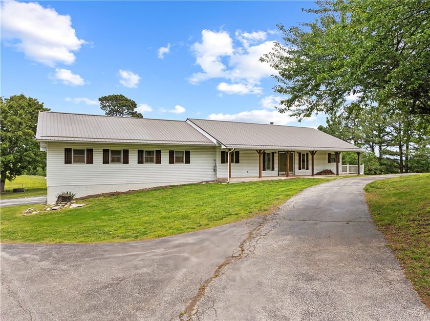 Some properties check the boxes. This one changes your pace.

Set on 37.56 acres of hilltop pasture & scattered woods, this 5-bedroom, 2.5-bath home offers the kind of privacy, views, & open space that’s getting harder to find. The covered back porch stretches the full length of the home, creating the perfect place to slow down, unwind, & take in the scenery. French doors from 4 bedrooms plus the main living area open directly onto the porch, bringing the outdoors into everyday life.

Inside, you’ll find wood ceilings, hardwood floors, oversized living spaces, recently updated full bathrooms, & a stunning 2-sided wood-burning fireplace that adds warmth & character. The property is set up for cattle with a 40x40 barn featuring a 10’ lean-to, a 3-car basement garage, circle drive, & covered front porch that complete the country feel.

Ideal for a hobby farm, ranch setup, hunting retreat, or anyone searching for acreage with usable land, storage, views, & room to spread out.