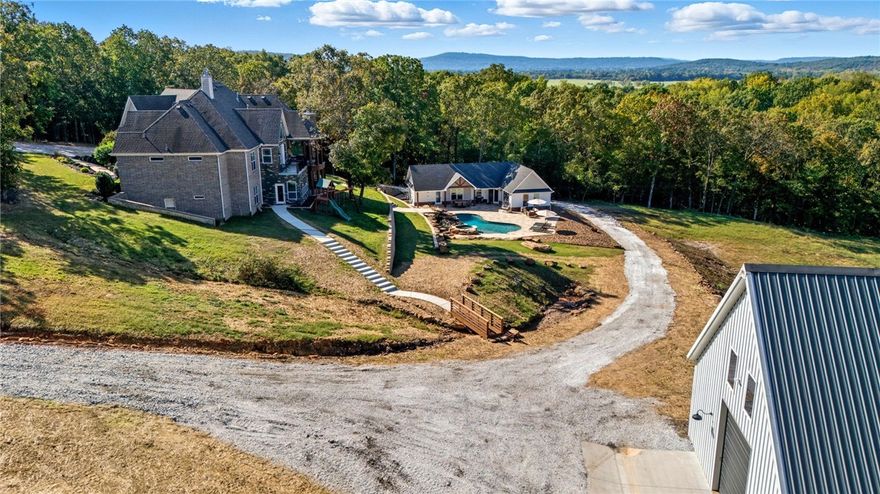 Tucked away at the end of a private gated drive in Autumn View, this exceptional estate spans approximately 12.5 acres of secluded beauty. Built in 2015 and thoughtfully updated, the 5,462 sq ft main residence offers 5 bedrooms, 5 baths (3 full + 2 half), an open eat-in kitchen flowing into the living area, formal dining, private study, and a walkout basement with kitchen/bar and entertainment space. A 1,337 sq ft pool house includes a full kitchen, living area, bedroom, bath, laundry, and gym with opposite end glass garage doors opening to the outdoors. Enjoy a heated inground pool with tanning ledge and spa and beautiful rock water feature, flagstone patio, outdoor shower, and professionally landscaped grounds. Additional highlights include a 40x80 detached garage with car lift,  epoxy-floored 3-car garage and whole-home Generac generator. You don't want to miss this East Fayetteville beauty.  Zoned for Vandergriff and McNair schools.