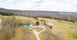 Country living with rustic comfort. This beautiful 3 bedroom,1 1/2 bath wood home sits on 20.42 acres with outstanding views and privacy. So many features! Attached 2 car garage leads into a large mud room. Spacious dining room/kitchen with all stainless-steel appliances and with over abundant cabinet space. Beautiful craftsmanship of all-natural wood 20' x 32' sunken living room/ den featuring vaulted wood beamed ceiling, many windows and new flooring. French doors lead to a fantastic stone patio complete with wet bar and fridge offering plenty of space for family cookouts and gatherings. Fenced pasture and barn make this property your dream farm!