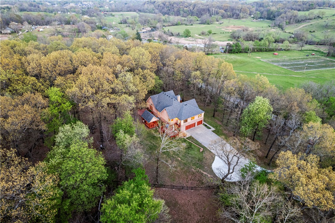Get ready for this rare unicorn of a property! Pull up to your private gated entrance that sits on 2.08 acres and is fully fenced. Located in the hottest area of NWA in a peaceful and private setting, yet just minutes to Hwy 112 making this the ultimate convenient oasis. Drive up your long driveway and into your oversized 3 car garage. The gorgeous trees are in abundance and make you feel like you are in a luxury tree house. Grand entry way with breathtaking views that make you want to rock on your front porch for hours. The main level offers a formal sitting room, an executive office, a great room open to the custom kitchen, a formal dining room, a wrap around sunroom, and the primary suite. Basement level offers a 3rd living space, 3 bedrooms, and a large laundry room. There's so much storage in this home at every turn! Book your showing today to come experience this one a kind property with an attractive price tag. This could be your next forever home. Ask your agent for the full list attached to the mls.