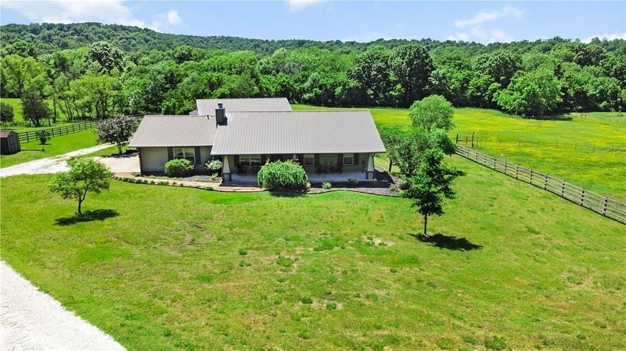 Situated on 6 acres on the Illinois River, this property provides direct river access & plenty of space to enjoy the outdoors. There are two living structures situated on the land, the main house and an apartment/shop. Apartment amenities include a single bedroom, full bath, wood burning stove, hot water heater, & washer dryer hookup plus a tack room. In the main house there is plenty of room to relax & entertain, the large living area flows seamlessly into the kitchen & out the covered patio - perfect for family gatherings. The large bathroom is shared by the two bedrooms with the primary bedroom attached. Both bedrooms offer ample space & views of the 6 acre property. This property is perfectly suited for those with hobbies like horseback riding, fishing, & floating. The apartment is connected to the barn with covered storage great for any hobby. Just a short drive to Farmington, Fayetteville, Prairie Grove, Lincoln or even Siloam Springs. Country living at its finest!