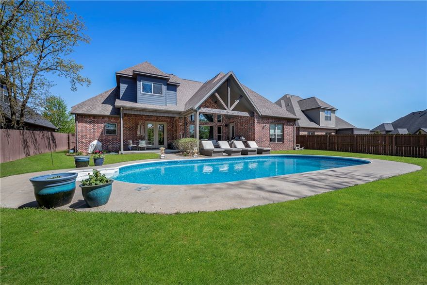 Don't miss this luxury home with pool in Woods Creek on an oversized half acre lot. This amazing home is open with vaulted ceilings, a gourmet kitchen and amazing space. You have 5 bedrooms, an office, a formal dining plus fantastic outdoor space including your own salt water pool. The pool is 9' deep and was put in in 2016. Inside the home you will love the hand-scraped hardwood floors and the transom glass over the door ways and beamed living room with real rock fireplace. This home is elegant but casual. The kitchen features a 6 burner cooktop, huge pantry, custom island with 6cm granite, there are two sinks and tons of cabinets space. There is also a mud room area with even more cabinets and extra storage under the steps. The primary suite is massive with hardwood floors, access to the patio and a spa like bath. There are 3 bedrooms on the main level then two more upstairs. Woods Creek gives you easy access to I49 and into downtown Bentonville.