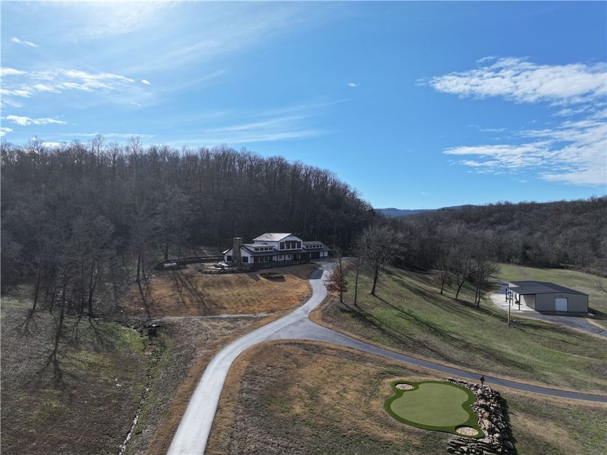 Welcome to your private Ozark Mountain retreat. Set on 80 scenic acres with the Middle Fork tributary running through the property, this exceptional estate blends luxury, recreation, and natural beauty.

The newly renovated main home offers 4 bedrooms, including 2 primary suites, an office, and 3 bathrooms. The separate in-law quarters feature a deck overlooking the pool and bluff line, plus 2 bedrooms, 1 bathroom, a living room, kitchen, and game area.

Enjoy poolside entertaining with a full-service bar and half bath. In cooler months, relax by the double-sided fireplace indoors or on the flagstone patio. Golf enthusiasts will love the on-site practice setup with a tee box just 100 yards from the putting green.

Additional highlights include a 50’ x 100’ shop with two new 14’ insulated doors, 10 hunting blinds, and a 200-yard shooting range. All just minutes from Fayetteville.