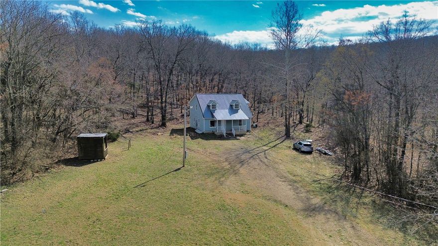 Discover the possibilities with this unique 34.5-acre property located less than 10 minutes from I-49 and approximately 20 minutes from Fayetteville. Offered as-is, this versatile tract blends natural beauty with usable land, ideal for a homestead, recreational retreat, or future development.

The property includes a house, cabin, and two additional outbuildings, offering multiple options for renovation, storage, or flexible use. The main house features recent updates, including new downstairs flooring, fresh paint, and other improvements, providing a refreshed interior with room for customization. A water well is located on the property, which sits outside city limits with no known restrictions, allowing for a variety of residential or agricultural uses.

The land showcases diverse terrain with mature trees, cleared areas, scenic bluffs, and a seasonal wet creek. Multiple potential homesites offer opportunities to expand, build, or create a private rural escape.