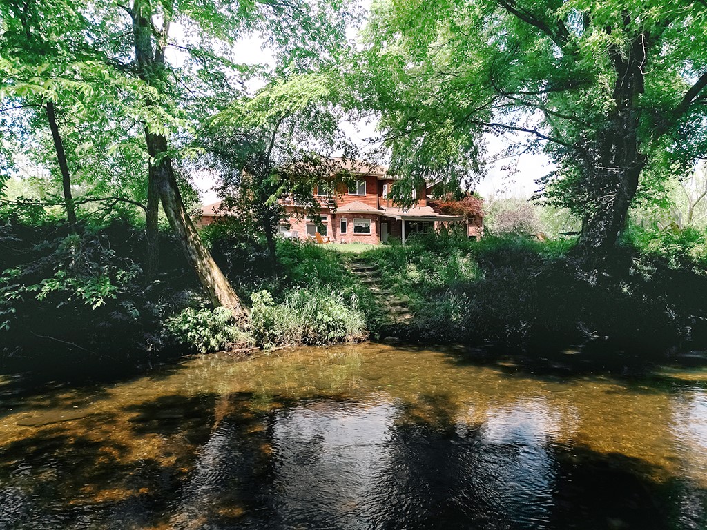 Out on the edge of town but an easy 15 mins to the city, sits a magnificent home on 4.7AC with over 400ft of gorgeous Goose Creek running across the back. Your new life would be hanging out in this back yard. The home itself is as pretty as its surroundings. Enter into a grand foyer with high ceilings, an impressive spiral staircase and a recessed living room w/gas fireplace, and a billiards room with a wet bar, mini-fridge and pool table. The huge kitchen has a double oven, gas cooktop, large fridge and pantry and eat-in kitchen, all of which opens up to the family room, with it’s cozy wood stove. The bedrooms are upstairs, including the primary with its massive en suite bathroom and attached office/bonus room. The 1344 sqft shop even has an extra guest room and bath. Solar panels, a whole-home dehumidifier, all new HVAC and upgraded siding and insulation were recently added, all to the tune of around $150K. And the owners are currently attempting to restore the pond in front to its former glory if possible.