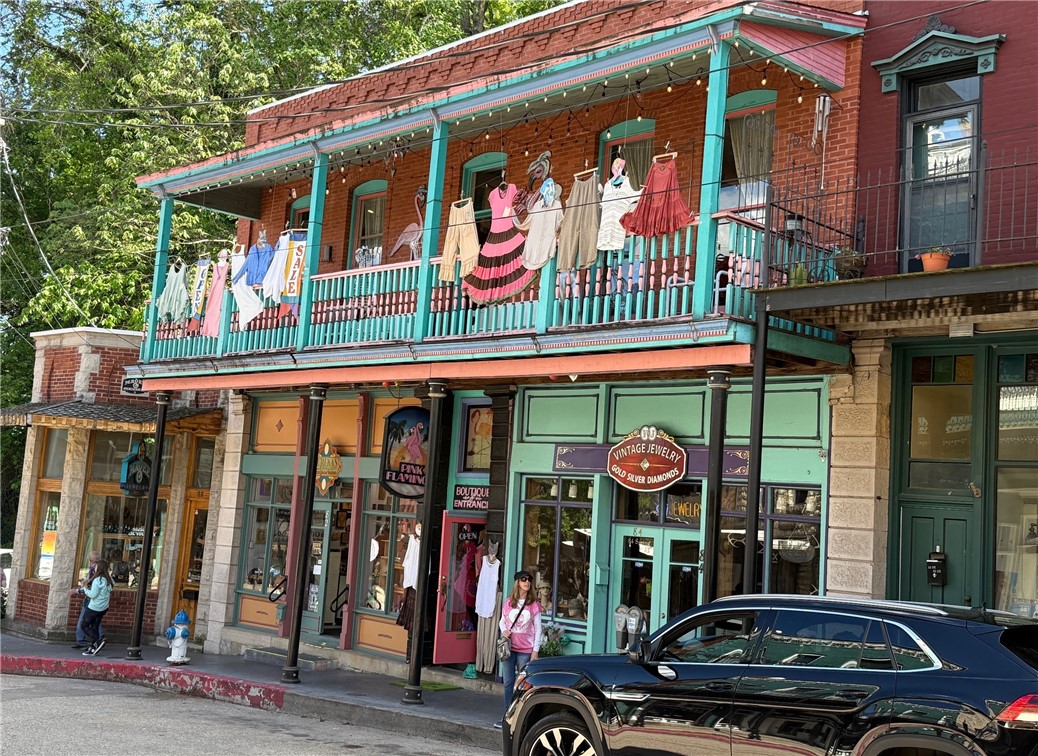 The Pink Flamingo Boutique has been the go-to destination for stylish womenās clothing and accessories in Eureka Springs since it opened more than 40 years ago. The shopās funky vibe keeps tourists and regulars coming to shop unique new arrivals. A whimsical flamingo sculpture and leopard-print carpet on the stairs easily coax shoppers up to the boutique. The interior's hardwood floors and warm wall color create a relaxed atmosphere for shopping. The covered porch is the perfect spot to display colorful merchandise to catch the eyes of tourists as they meander up Spring Street. Encompassing the entire second floor of the building with 1,596 sq. ft., the shop could be divided into two smaller spaces like the two lower storefronts. The space could include an ownerās apartment since a kitchen and a full bath with a tub/shower complete the floor plan. C-1 commercial zoning allows for a number of uses. New roof in April 2025. Seize the opportunity to own a proven business location in downtown Eureka Springs.