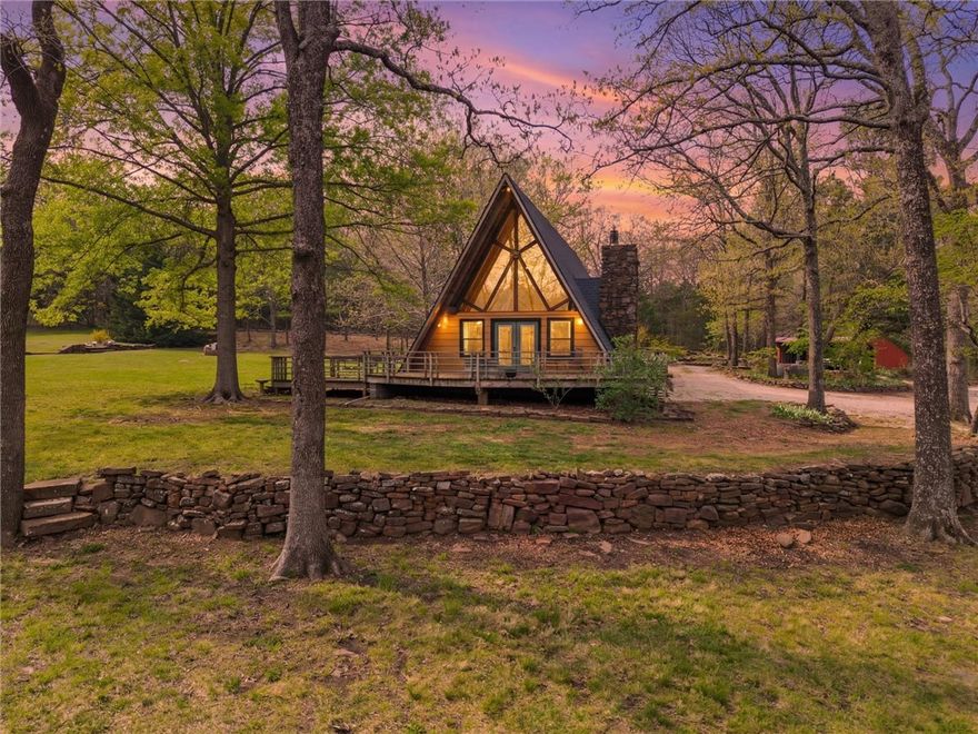 Whether you are looking for a permanent home or a weekend retreat, this property has a lot to offer. Surrounded on three sides by rolling hills and natural forest, the peaceful valley setting is beautiful in all seasons, but stunning in the fall. Minutes from Historic Canehill, the remodeled A-frame home sits just down a well-maintained gravel road with easy access from Fayetteville, Ft. Smith, or Siloam Springs. Nice mixture of woods and open fields along with a pond and wet weather creek. ATV trails run throughout the property. The end-of-the-road location offers privacy, seclusion, and peace. The charming cabin has been completely remodeled but retains the 1970s charm with its vaulted ceilings, wall of windows, stone fireplace, and original pine floors. Don’t miss the recent (2025) barn conversion with its additional bath, full kitchen, and extra storage. There is City water and a well that is plumbed to supply the A-frame, guesthouse, and gardens. Additional acreage available see MLS 1342083