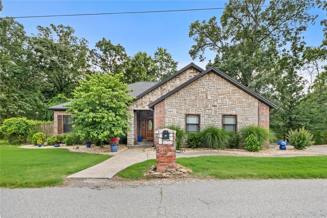 Nestled on the scenic Grandshire Drive loop, just minutes from the Metfield Rec Center, this beautifully maintained stone and brick home offers comfort, charm, and convenience. Step inside to an inviting open-concept living area featuring cathedral ceilings, a cozy fireplace, and gleaming wood floors. The spacious kitchen includes a pantry, a breakfast nook, and a versatile bonus space perfect for formal dining or a home office. With three generously sized bedrooms and two full bathrooms—including a recently upgraded primary suite shower—this home is both functional and stylish. Relax or entertain on the covered back porch surrounded by mature trees and natural privacy. Seller also installed Everlights so you can be festive all year round!