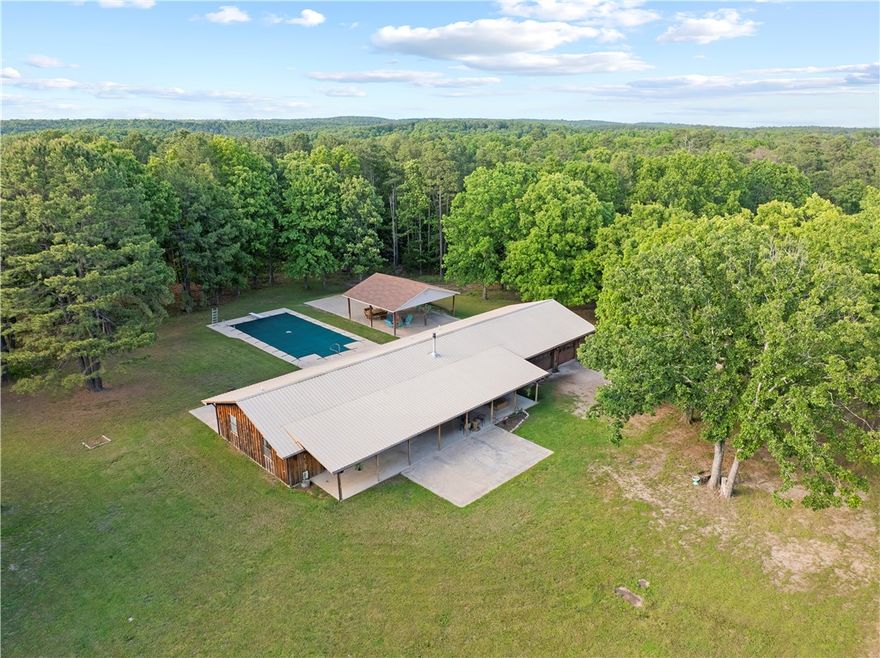 Hidden among the trees on 105 +/- acres, this private and secluded property offers the space, freedom, & versatility so many buyers are searching for. The 3 bed, 2 bath home features a massive kitchen with a large center island, spacious living area with a wood-burning stove for added warmth & character, and a primary bathroom with a whirlpool tub/shower combo. A covered front porch stretches the full length of the home, creating the perfect place to unwind and enjoy the peaceful setting. Outside, you’ll find an in-ground pool, a 70x50 shop with water & electricity, and THREE working wells already in place — opening the door for future homesites, additional construction, or investment potential. Hunt, farm, ride ATVs, or create your own private retreat, all while being just 20 minutes from a marina & boat ramp on Bull Shoals Lake. Properties like this rarely hit the market.