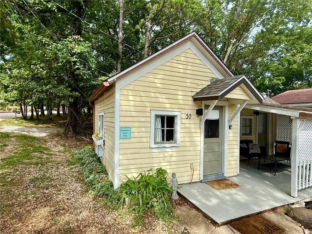 Turn-Key VRBO with Commercial Zoning and Off-Street Parking! You'll enjoy this Eureka Springs getaway on the Upper Historic Loop that currently operates as a successful nightly tourist lodging. The historic cottage once served as a one-room schoolhouse and has all the charm you could imagine reflecting a relaxed cottage style. The covered porch is accessible from the kitchen making it a great place to entertain. The property is zoned commercial which allows for numerous uses. A great location close to downtown with off-street parking. Cottage style furnishings convey. Short jaunt to your favorite shops and restaurants and also on the trolley route. Short bike ride to Black Bass Lake trail system. Within a block of the Eureka Springs Community Center and Farmer's Market. Recently remodeled bathroom with a tiled shower. New roof in December 2024.